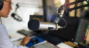 microphone in a podcasting studio, host and the broadcasting equipment in the background